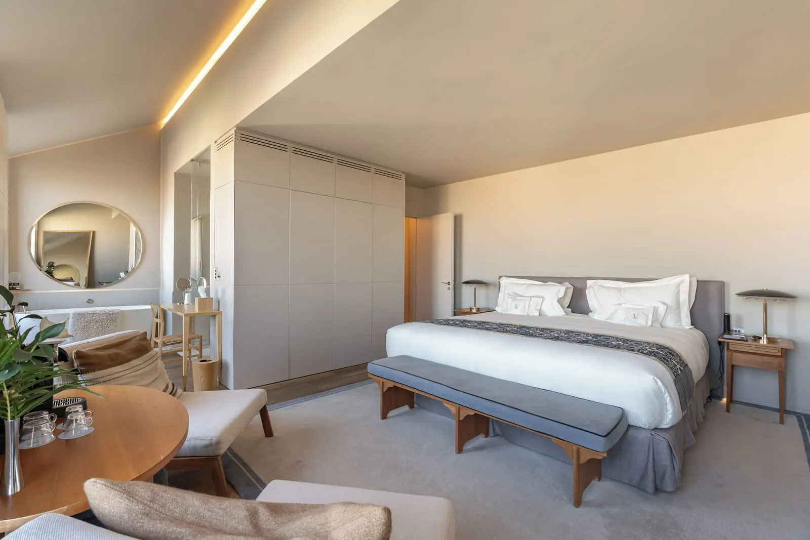 Junior Suite at Verride Palácio Santa Catarina: the bed with a bench at its foot, a round mirror and a table with armchairs
