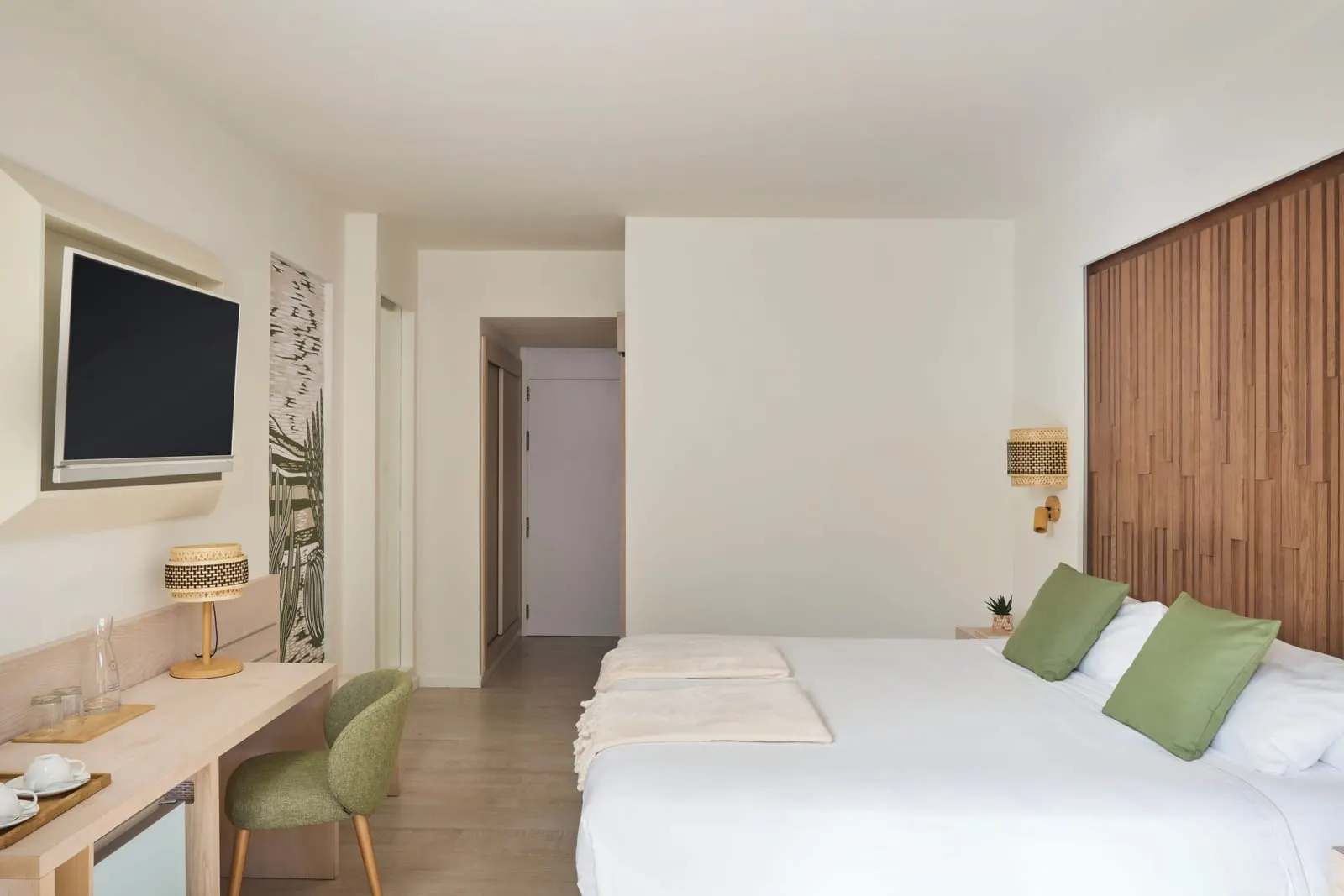Double im Iberostar Selection Fuerteventura Palace: zwei bezogene Einzelbetten nebeneinander unter einem Kopfteil aus Holzlatten, mit grünen Kissen, einem Schreibtisch und einem Wandfernseher