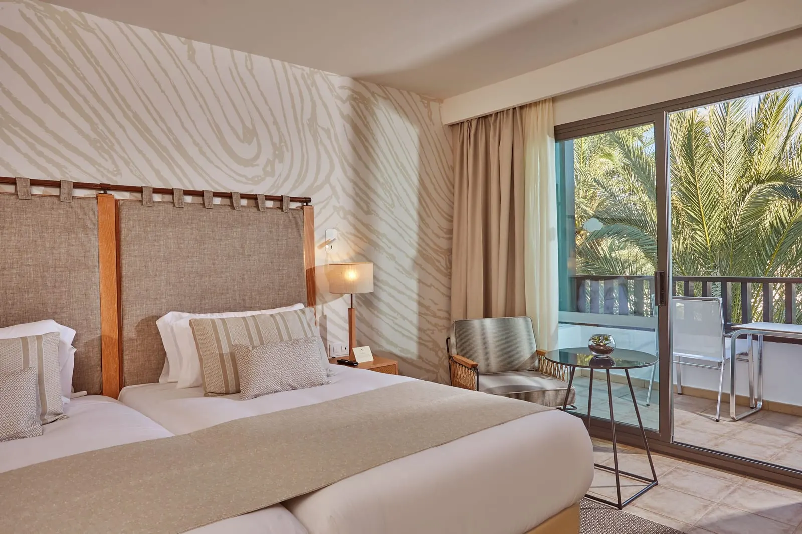 Preferred Club Deluxe Ocean View al Secrets Lanzarote Resort & Spa: un letto accanto a porte aperte sul balcone con palme e un tavolo sul balcone all'esterno