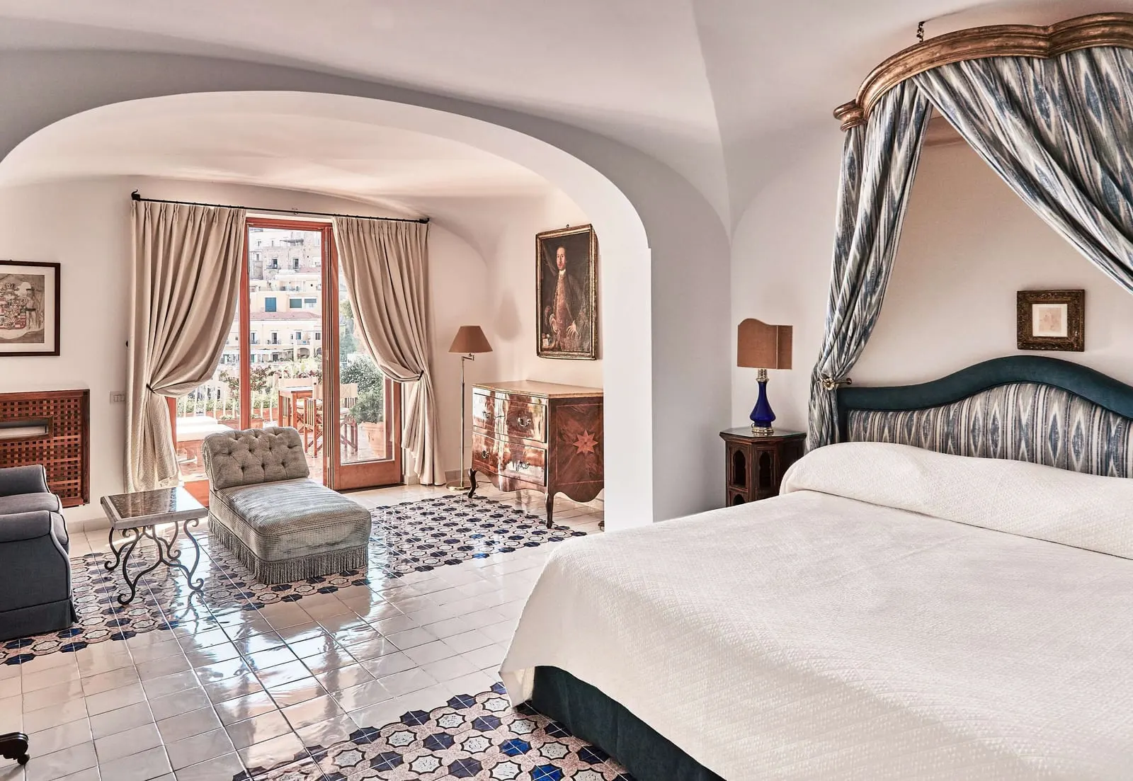 Junior Suite Sea View at Le Sirenuse: a canopied bed, with an arch through to a sitting area and doors open to a terrace