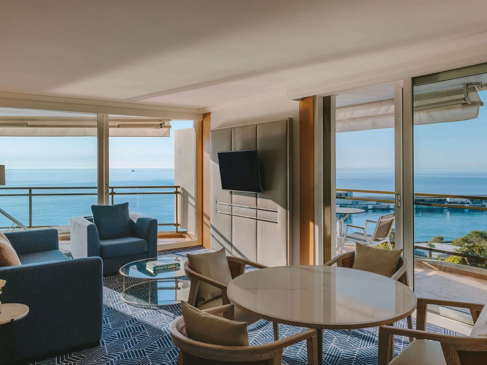Commodore Suite Sea View at Fairmont Monte Carlo: the living and dining room with windows to the sea on two sides