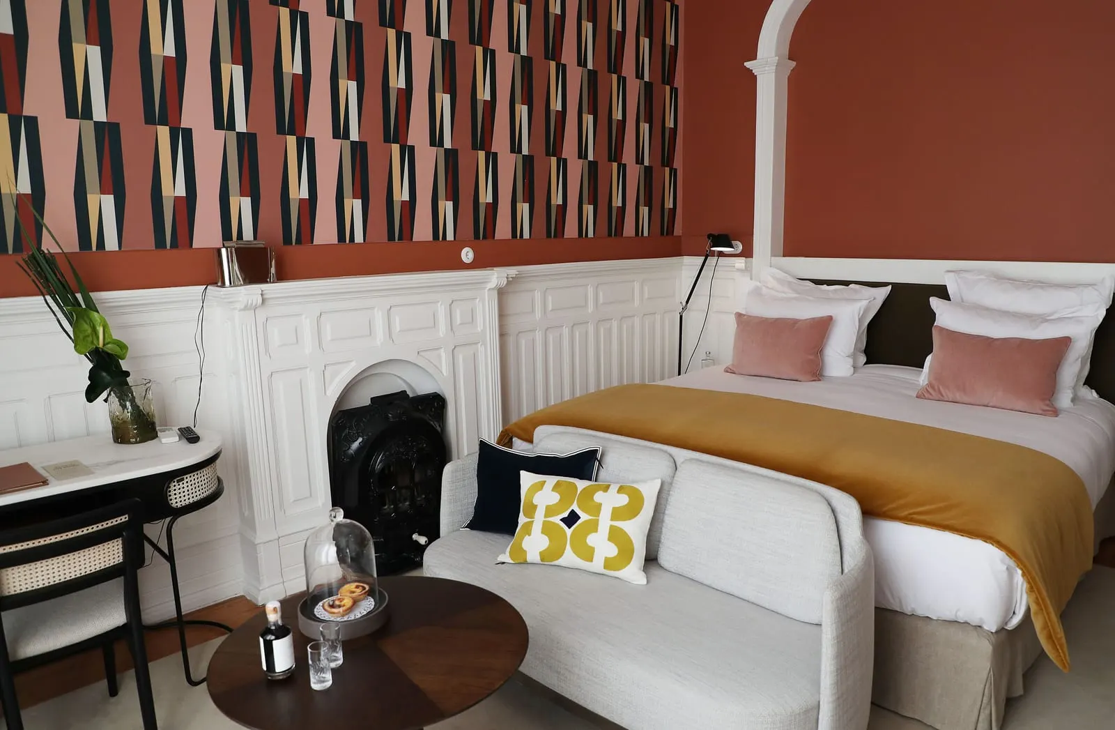 Lisboa Room at Sublime Lisboa: the bed, a white sofa, a desk and a panelled fireplace below patterned wallpaper