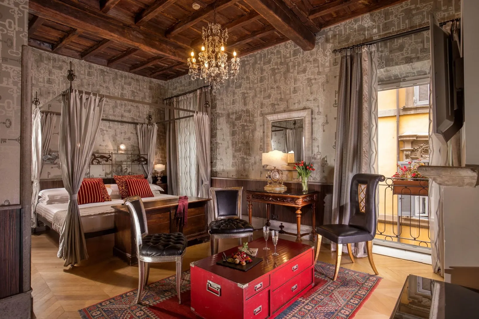 Junior Suite at The Inn at the Roman Forum: a canopy bed, a desk, a red chest and an open balcony door