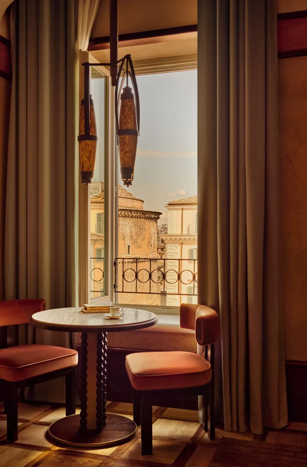 Junior Suite with View at Orient Express La Minerva: a table for two at a tall open window with a balcony rail, rooftops outside
