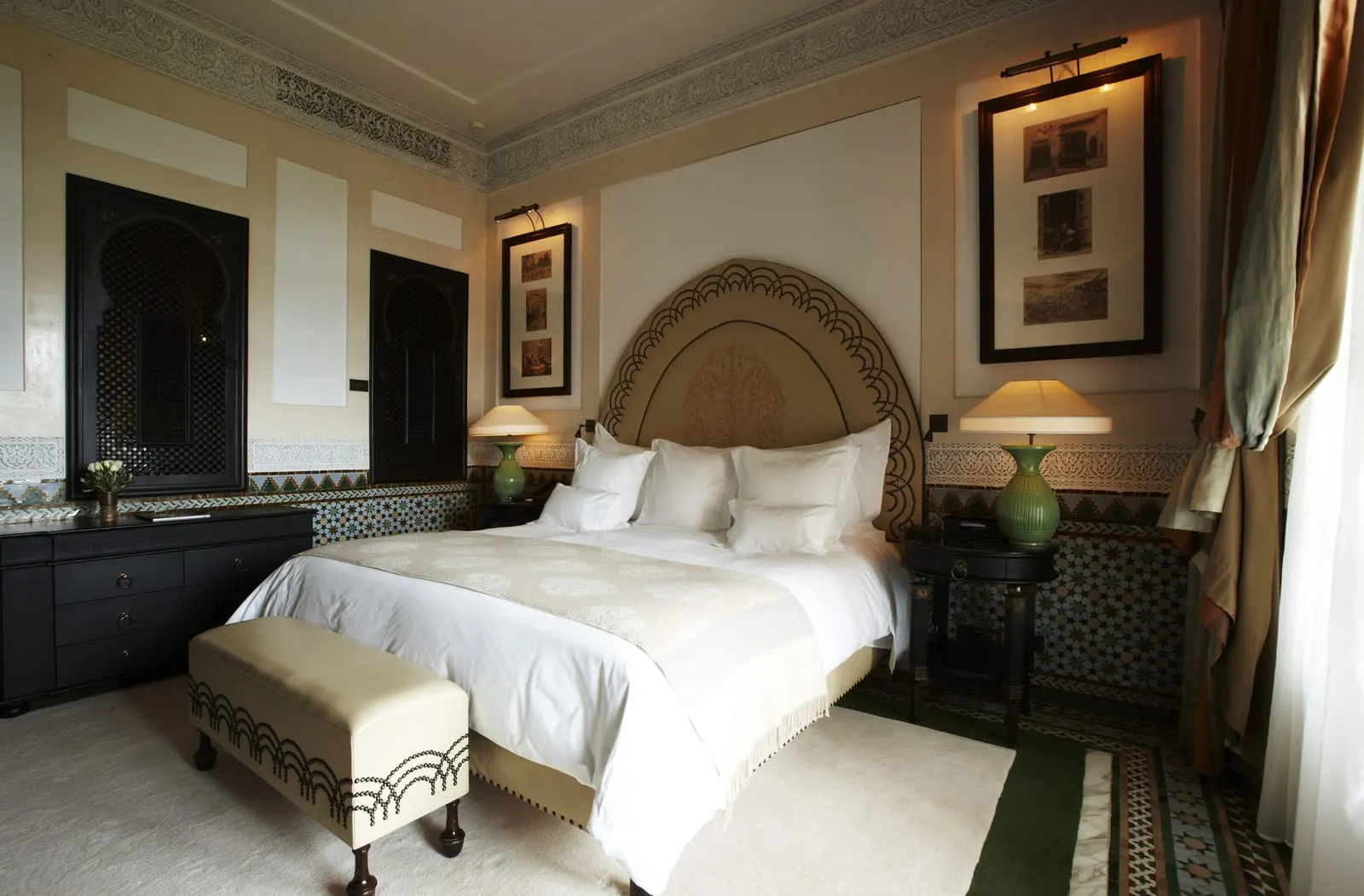Park Deluxe Room at La Mamounia: a king bed with a cream bench at its foot, green lamps and a zellige tiled dado