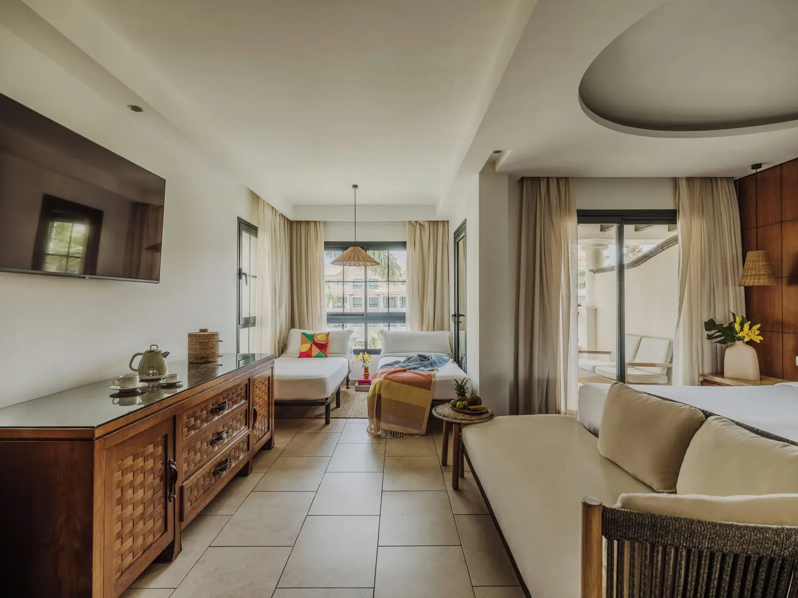 Deluxe Family at Gran Meliá Palacio de Isora: two single beds by the far window, a long sideboard and a sofa