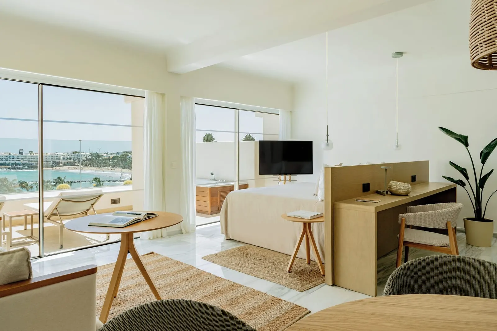 The Reserve Junior Suite Ocean Front With Whirlpool at Paradisus Salinas Lanzarote: a lounge and desk beside a large window over a terrace
