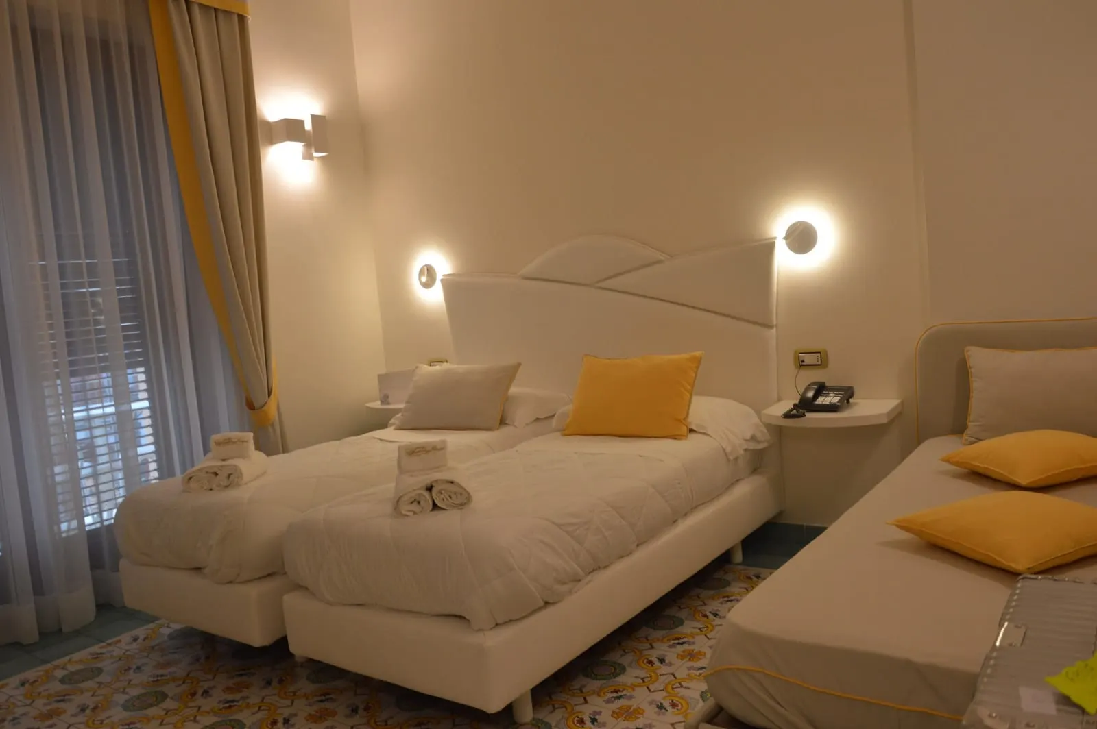 Classic Triple at Hotel Santa Lucia: two beds pushed together under a white headboard, with a third bed alongside and a curtained window