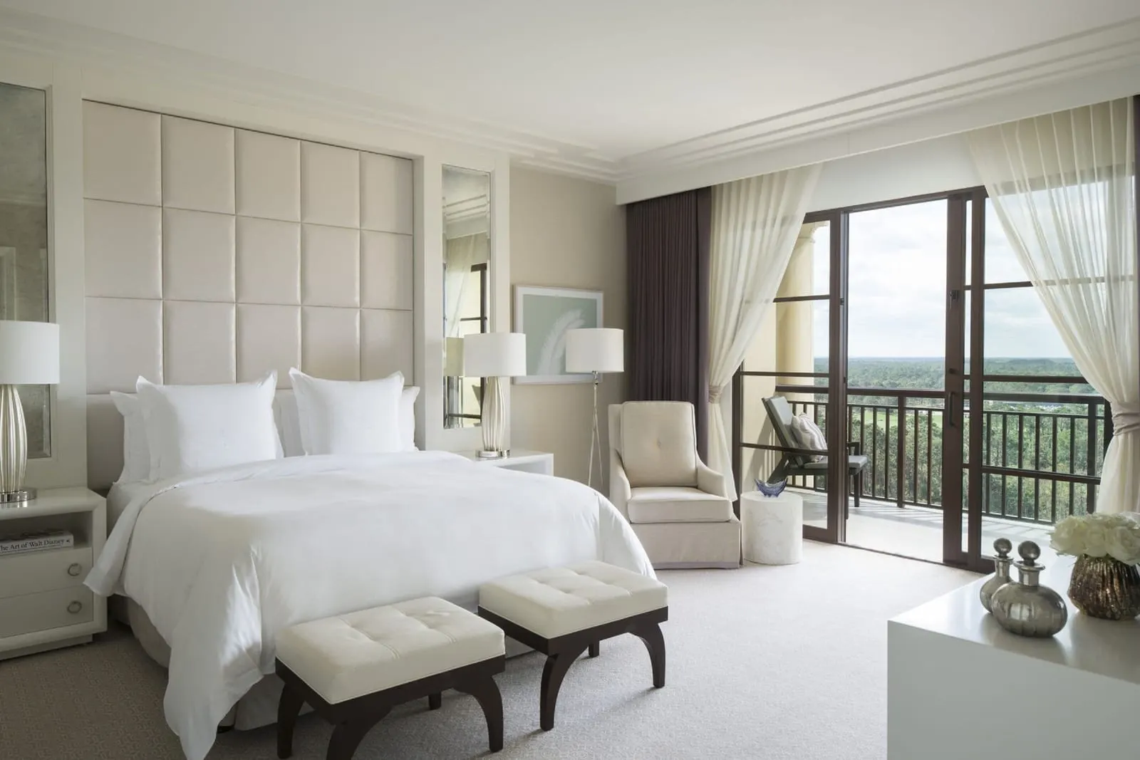 Grand Suite im Four Seasons Resort Orlando at Walt Disney World Resort: das Schlafzimmer, mit einem Kingsize-Bett vor einer gepolsterten Wand, einem Sessel und Glastüren zu einem Balkon