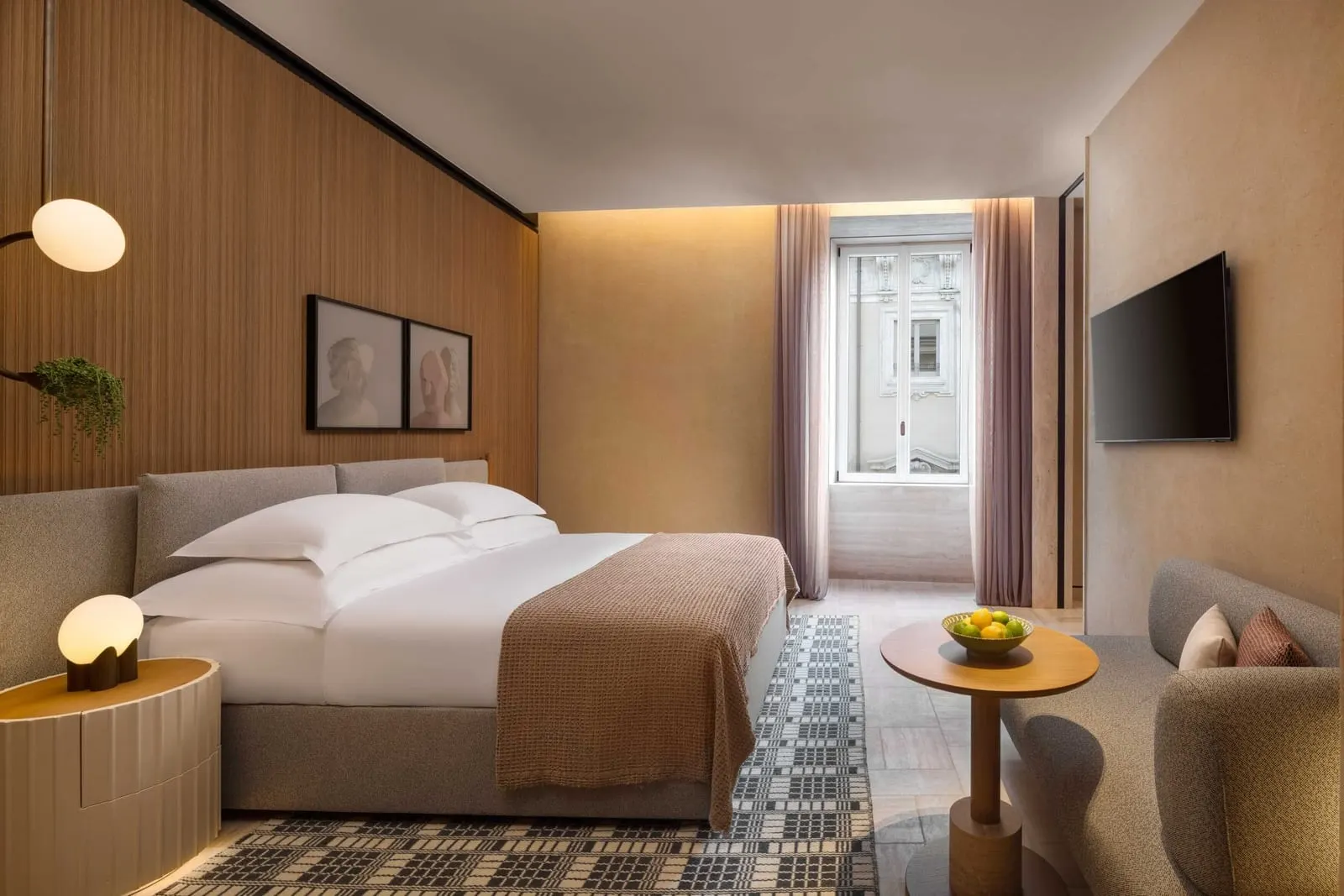 Junior Suite at Six Senses Rome: the bed facing a tall curtained window, with a sofa and a round table