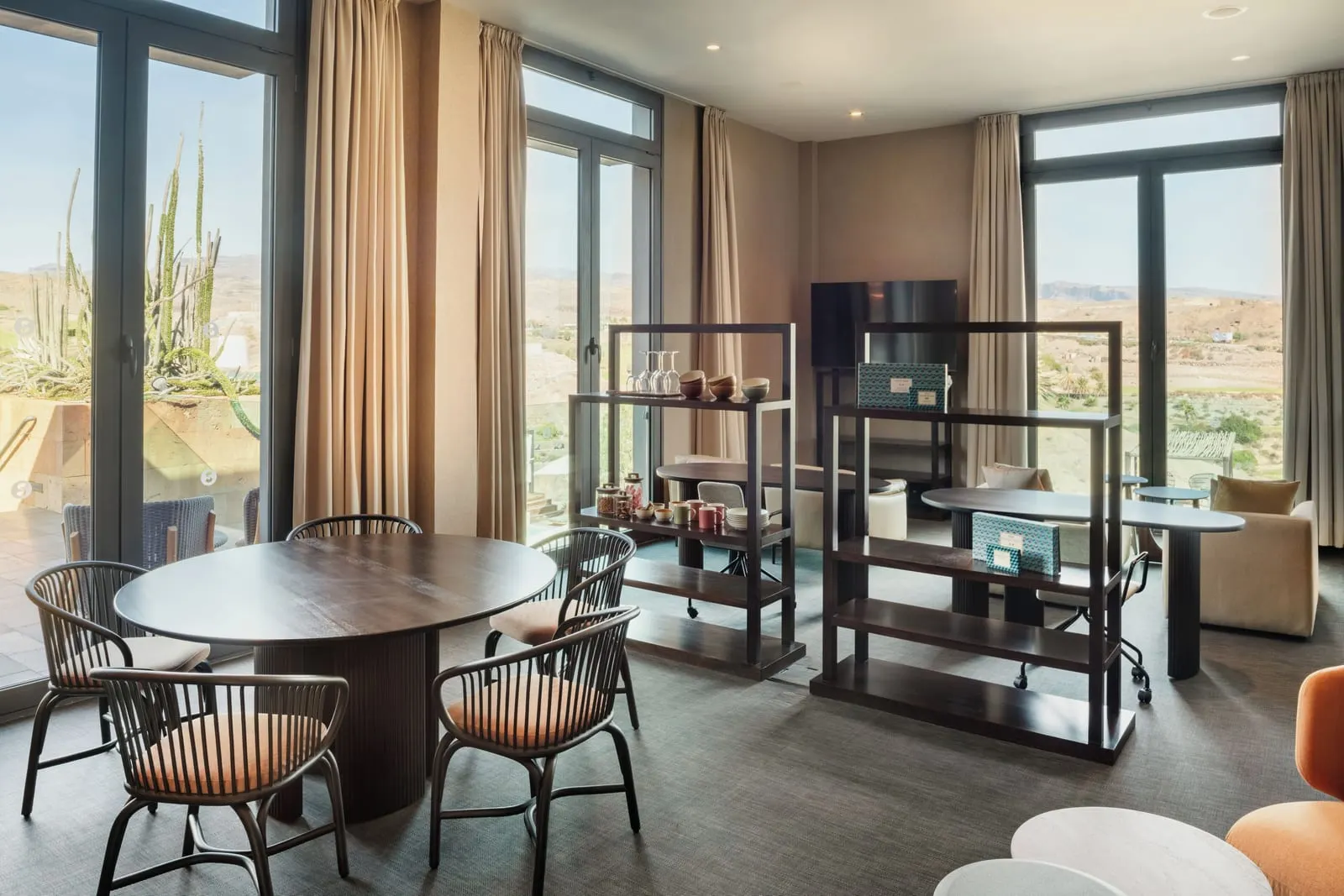 eSencia Double Deluxe Superior at Salobre Hotel Resort & Serenity: the eSencia lounge, with a round table and chairs, open shelves of cups and glasses, and desks by tall windows