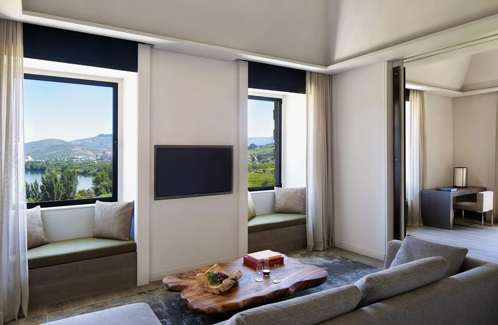 Quinta Courtyard Suite at Six Senses Douro Valley: a sofa, a wooden coffee table and window seats looking over the river