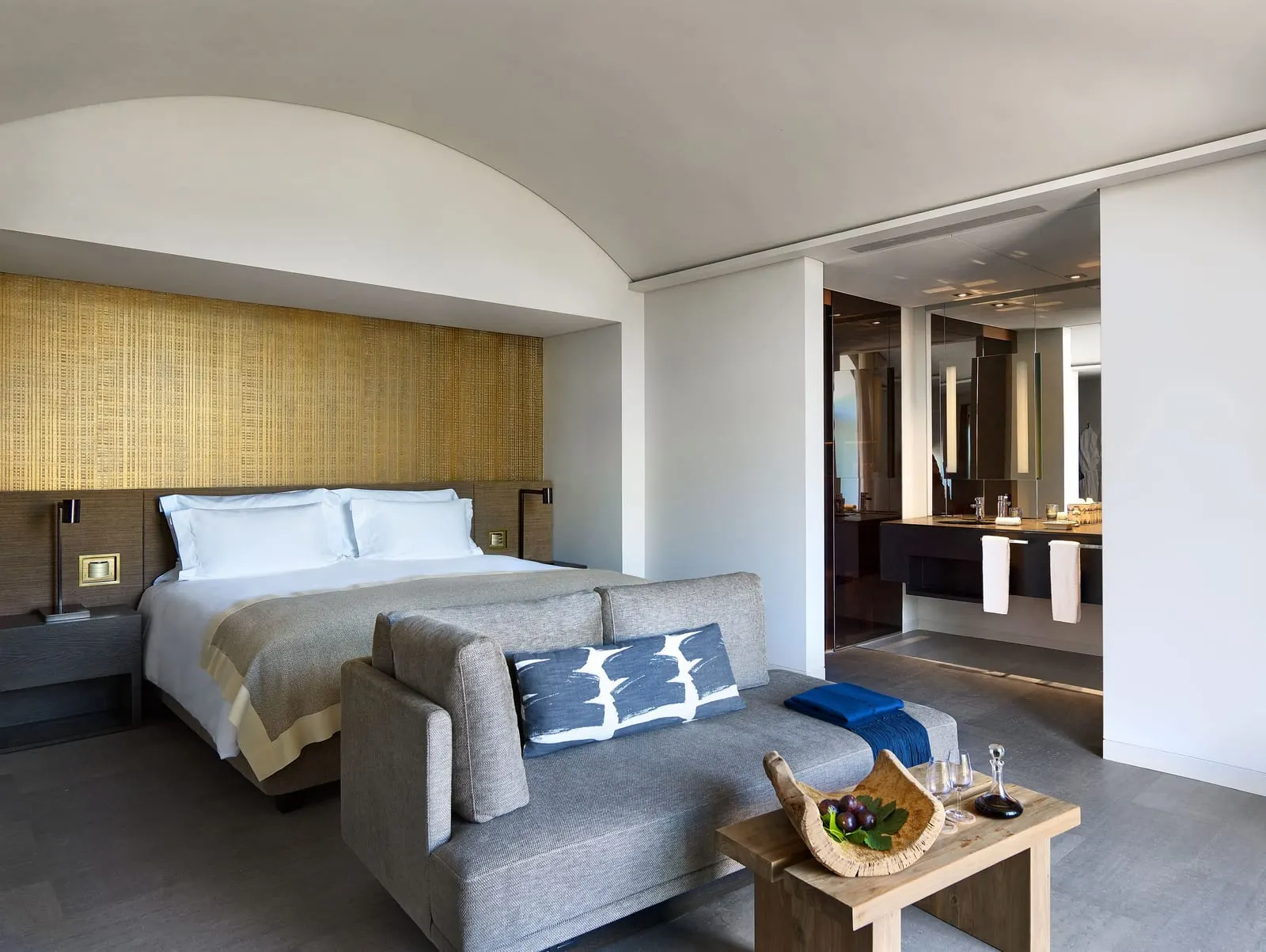 Quinta River at Six Senses Douro Valley: the bed under a vaulted ceiling, a sofa at its foot and the open bathroom beyond