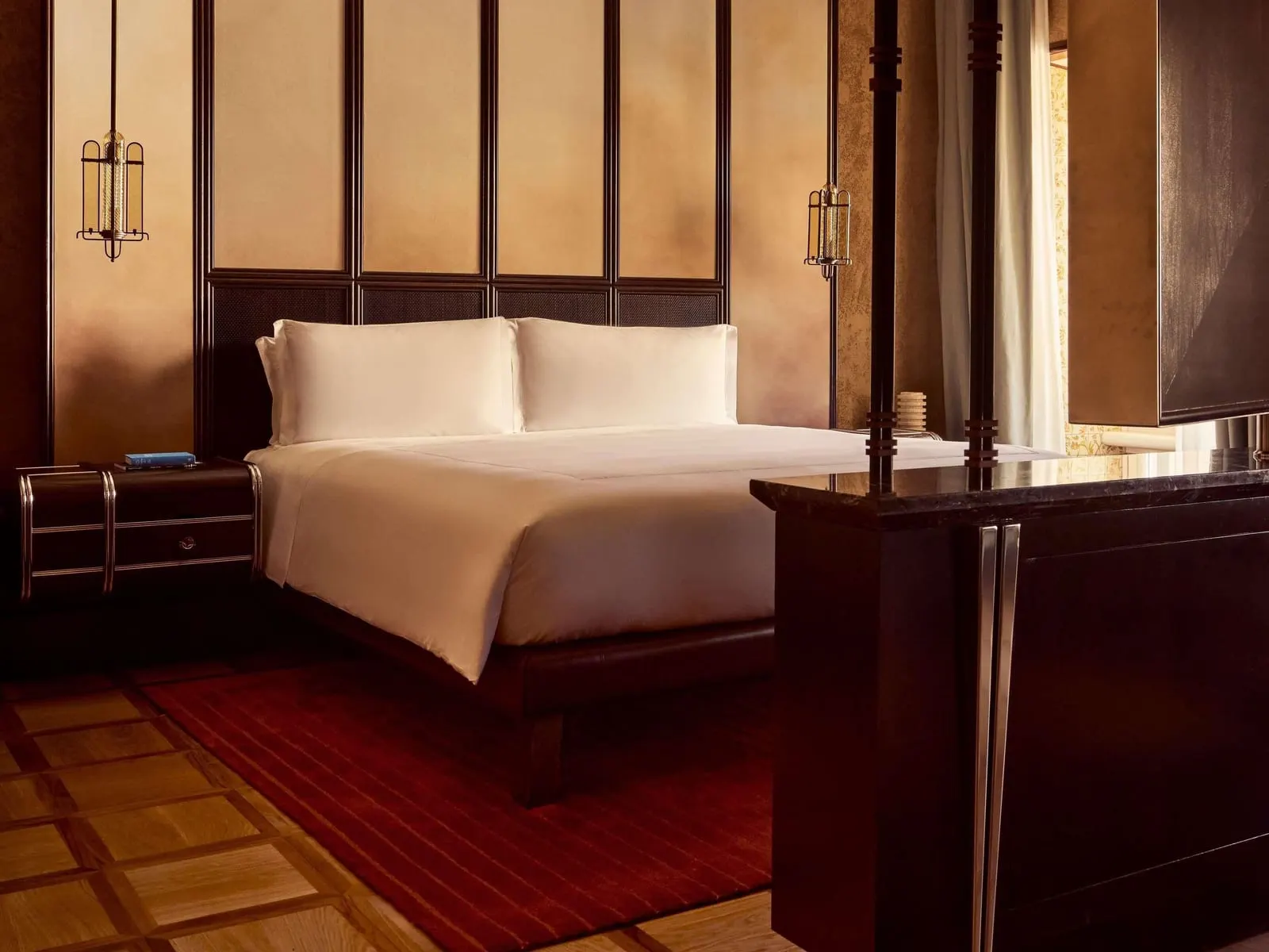 Junior Suite with View at Orient Express La Minerva: the bed against a panelled headboard, a dark cabinet in the foreground