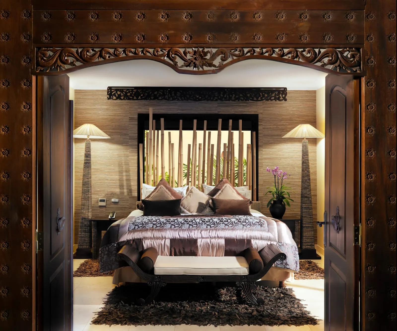 Gran Duchess Villa at Royal Garden Villas: the bedroom seen through carved wooden doors, a bench at the foot of the bed