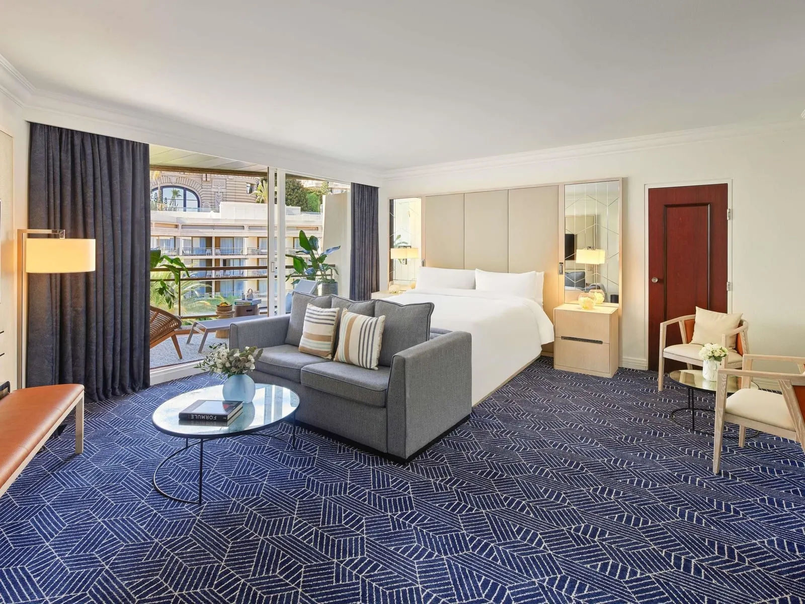 Junior Suite Garden View at Fairmont Monte Carlo: a sofa and coffee table before the bed, the terrace beyond