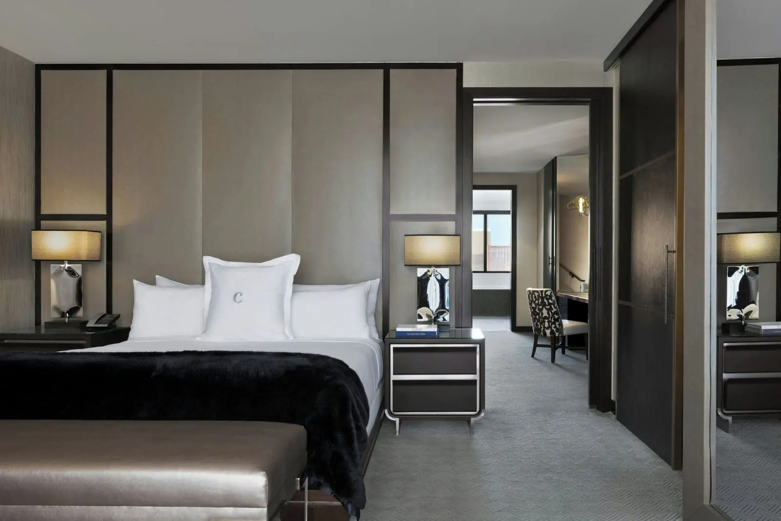 Bungalow at The Cosmopolitan of Las Vegas: the bedroom, with a bed under a black fur throw, panelled walls and a sliding dark wood door