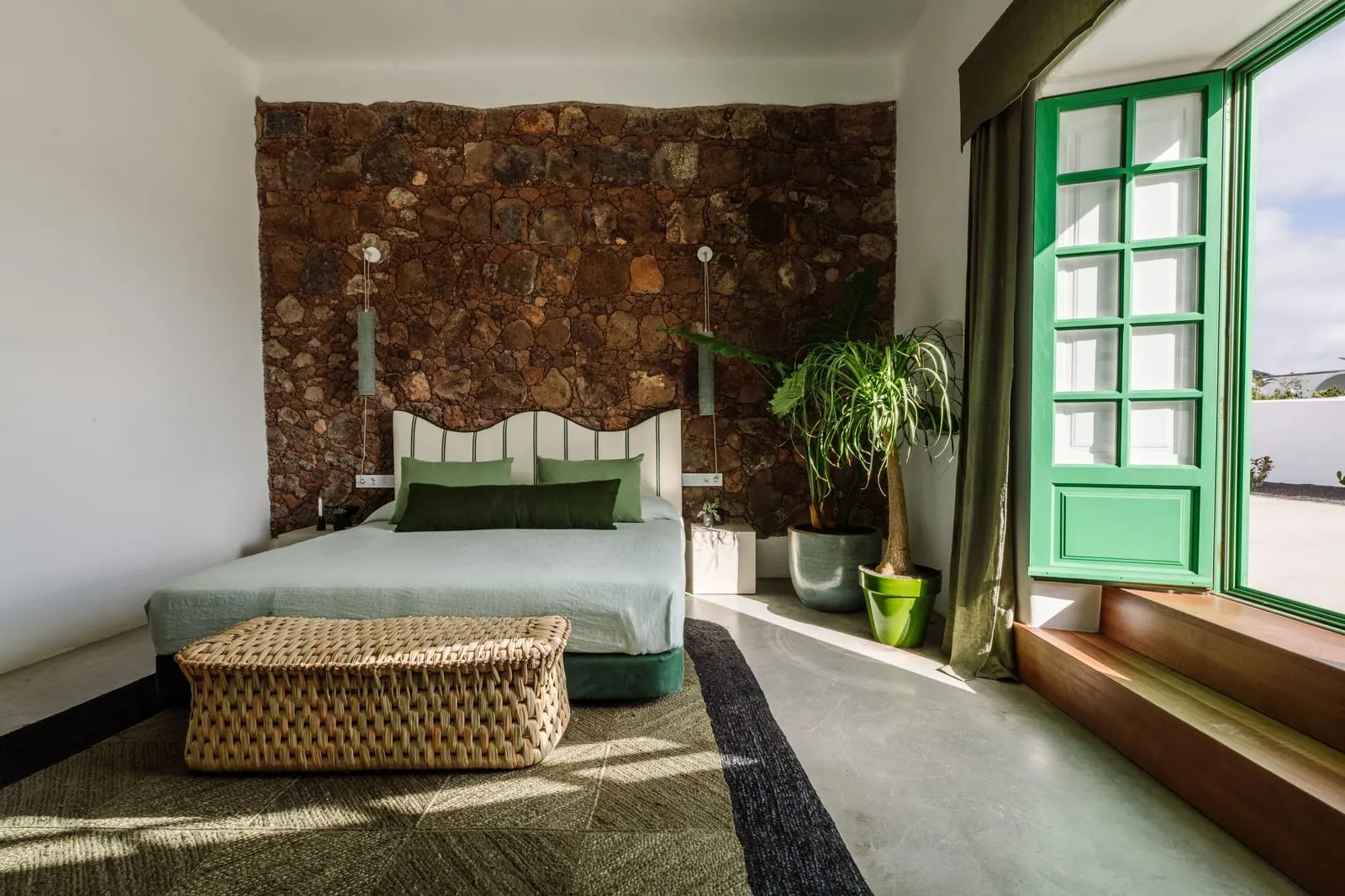 Suite with Terrace and Volcano View à l'Hotel César Lanzarote : un lit avec une tête de lit festonnée contre un mur en pierre volcanique, près d'une fenêtre verte
