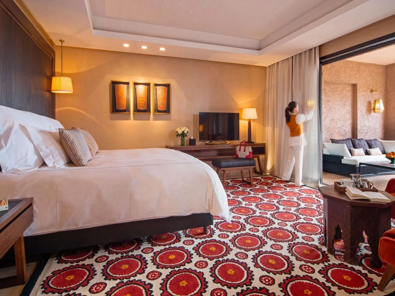Deluxe Suite Atlas View im Fairmont Royal Palm Marrakech: ein Kingsize-Bett auf einem roten gemusterten Teppich, dahinter ein Lounge-Bereich