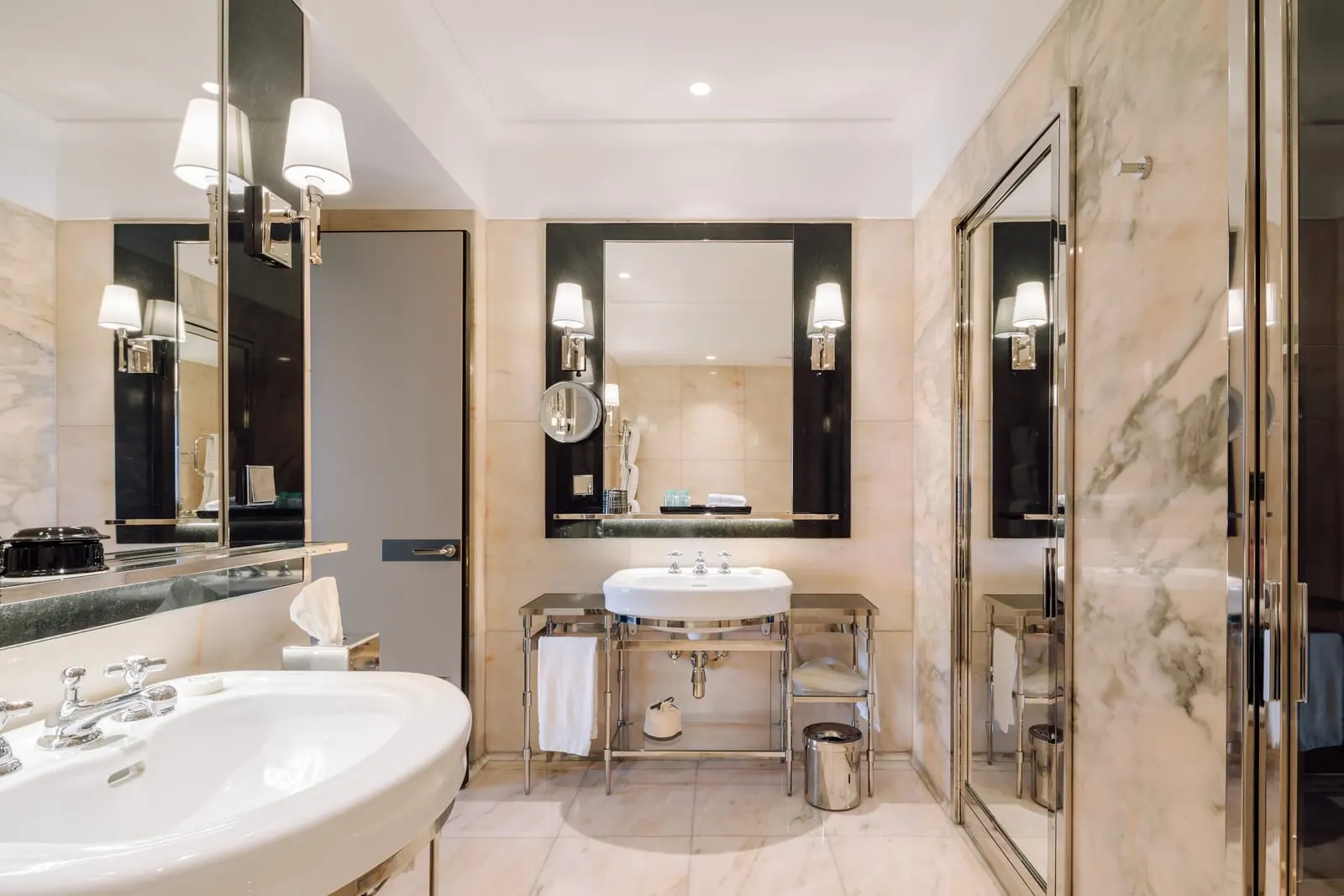 Deluxe Park-View Room bathroom at Four Seasons Ritz Lisbon: marble walls, a basin on a metal stand and a glass shower