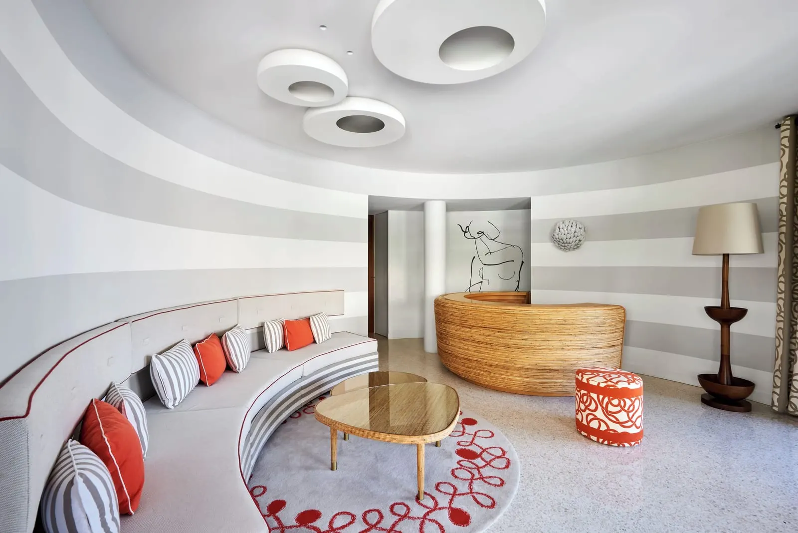 Duplex Suite at Monte-Carlo Beach: a curved banquette with orange cushions and a glass coffee table
