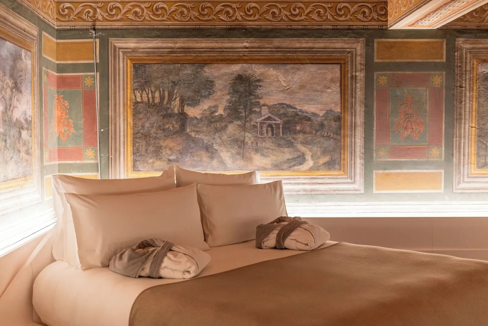Fresco Junior Suite at ROMEO Roma: the bed under a painted landscape of trees and a small temple, between red panels