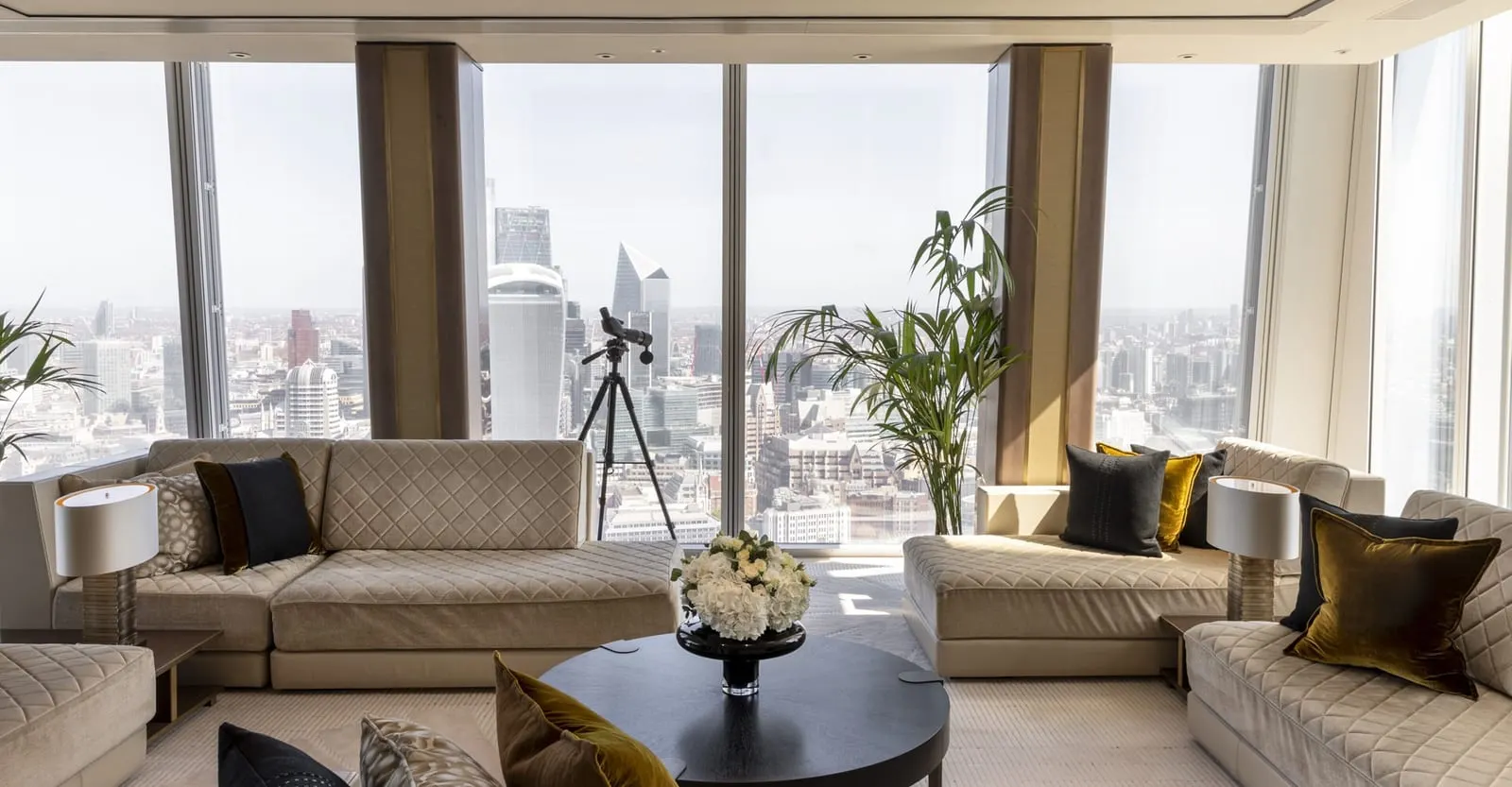 Shangri-La Suite at Shangri-La The Shard: the living room with sofas and a telescope before a wall of windows