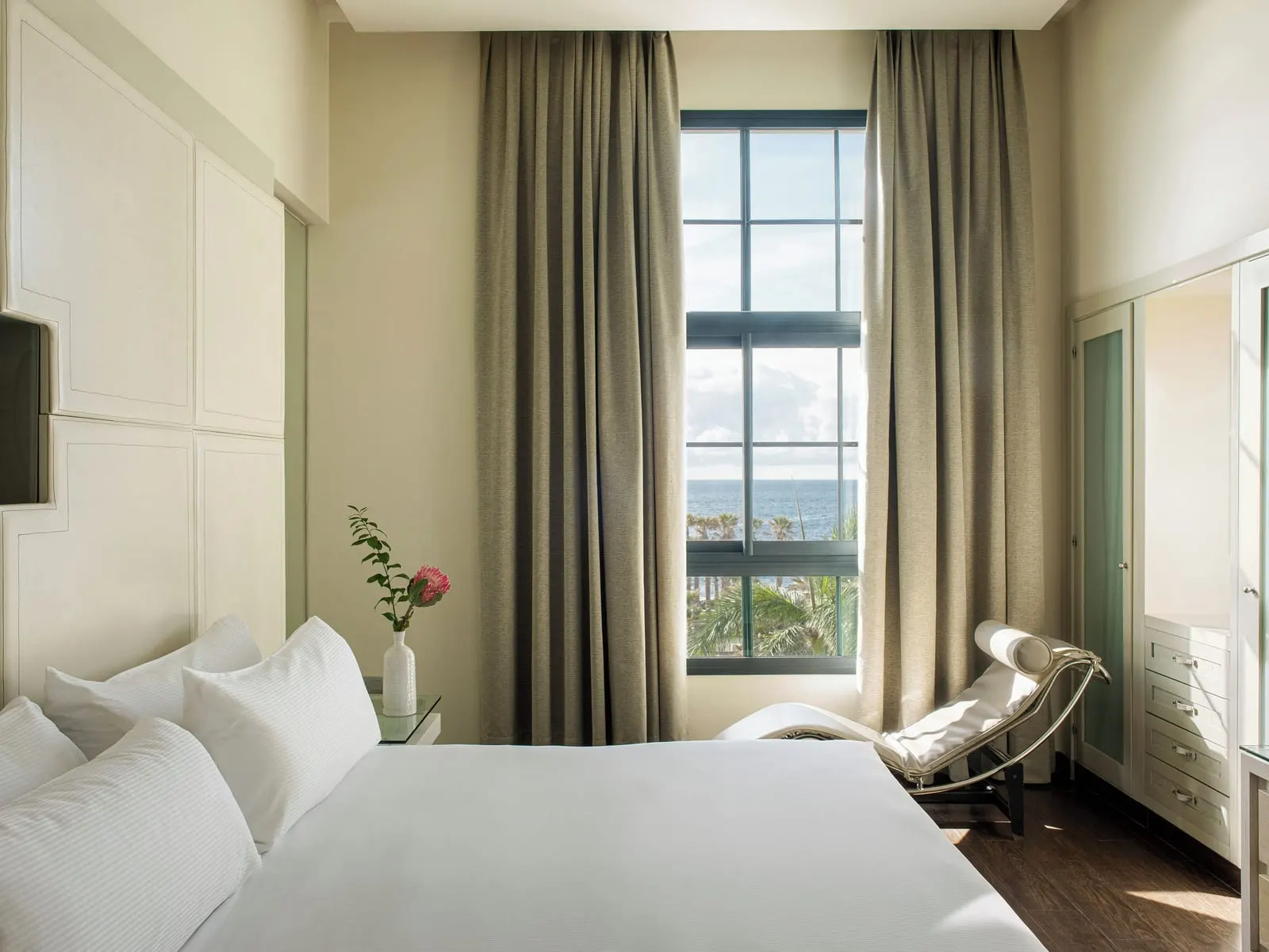 RedLevel Master Suite Two Bedrooms Ocean View at Gran Meliá Palacio de Isora: a bedroom, a lounge chair and a tall window