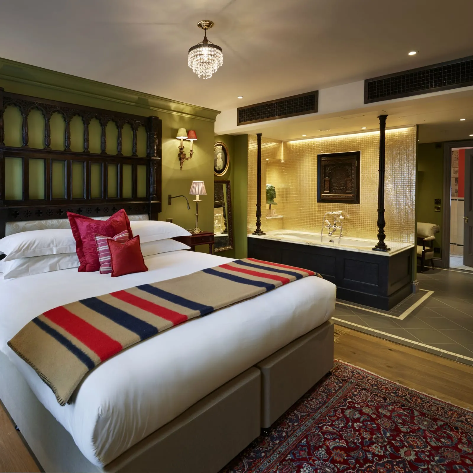 Junior Suite at The Zetter Marylebone: the bed with a carved green headboard and a lit bath area beyond