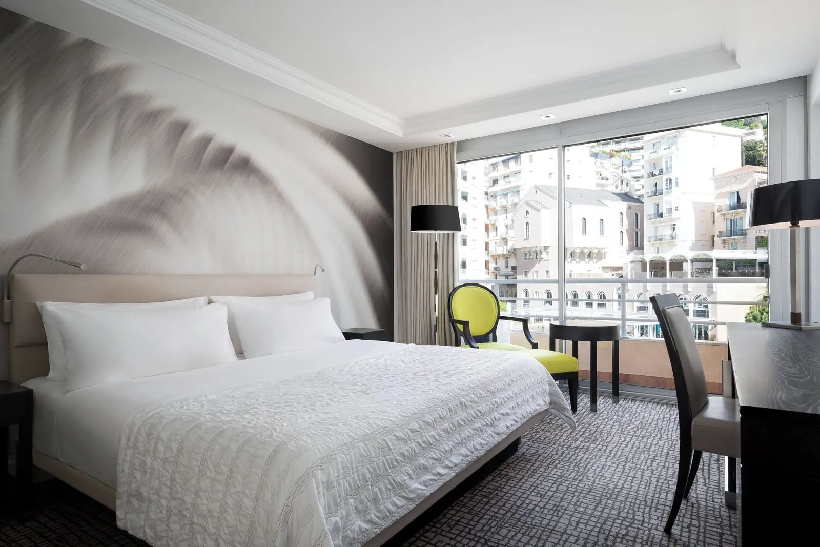 Classic room at Le Méridien Beach Plaza: the bed, a yellow armchair and a desk by a window onto apartment buildings