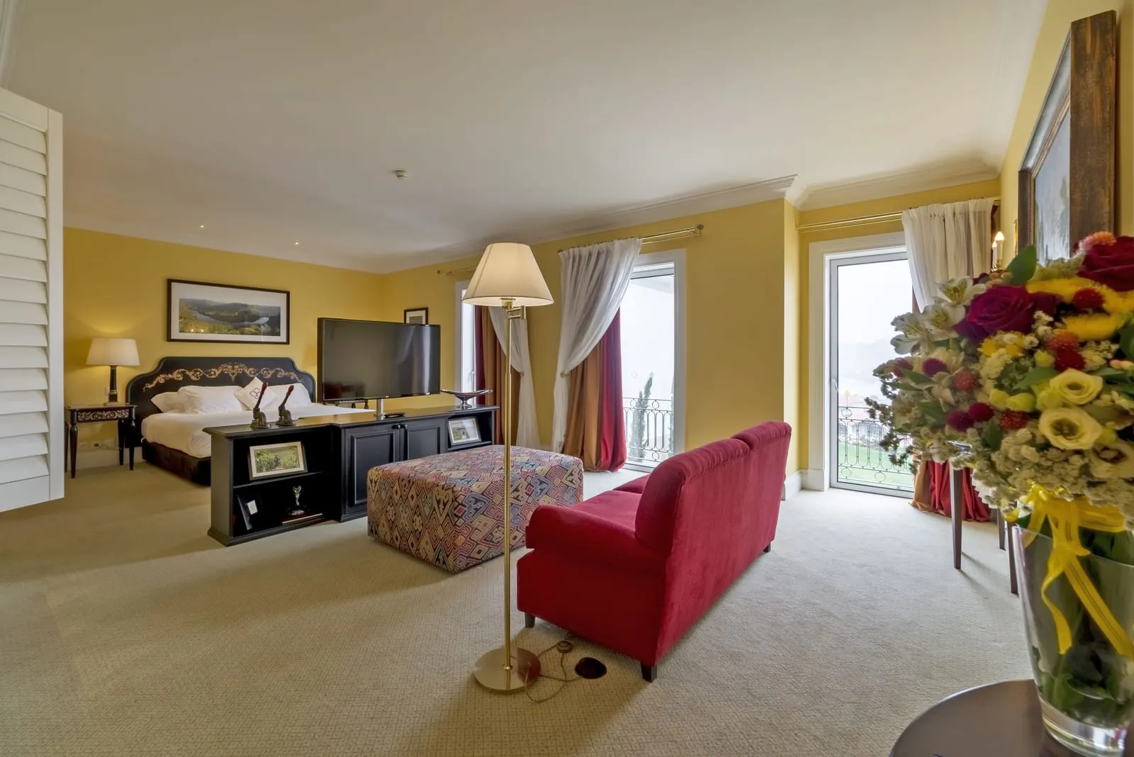 Suite at The Yeatman: the bed and a television cabinet at one end, a red sofa and a patterned ottoman in the sitting area