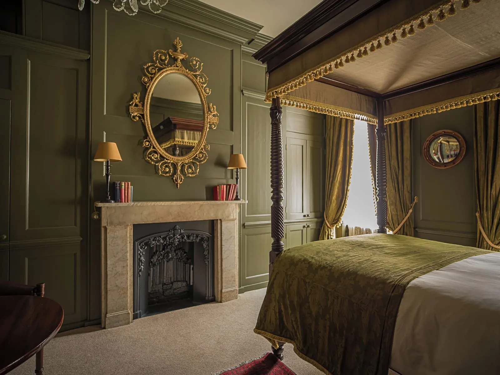 Luxury Double al Hazlitt's: un letto a baldacchino, un camino in pietra e uno specchio dorato su pareti rivestite in legno verdi