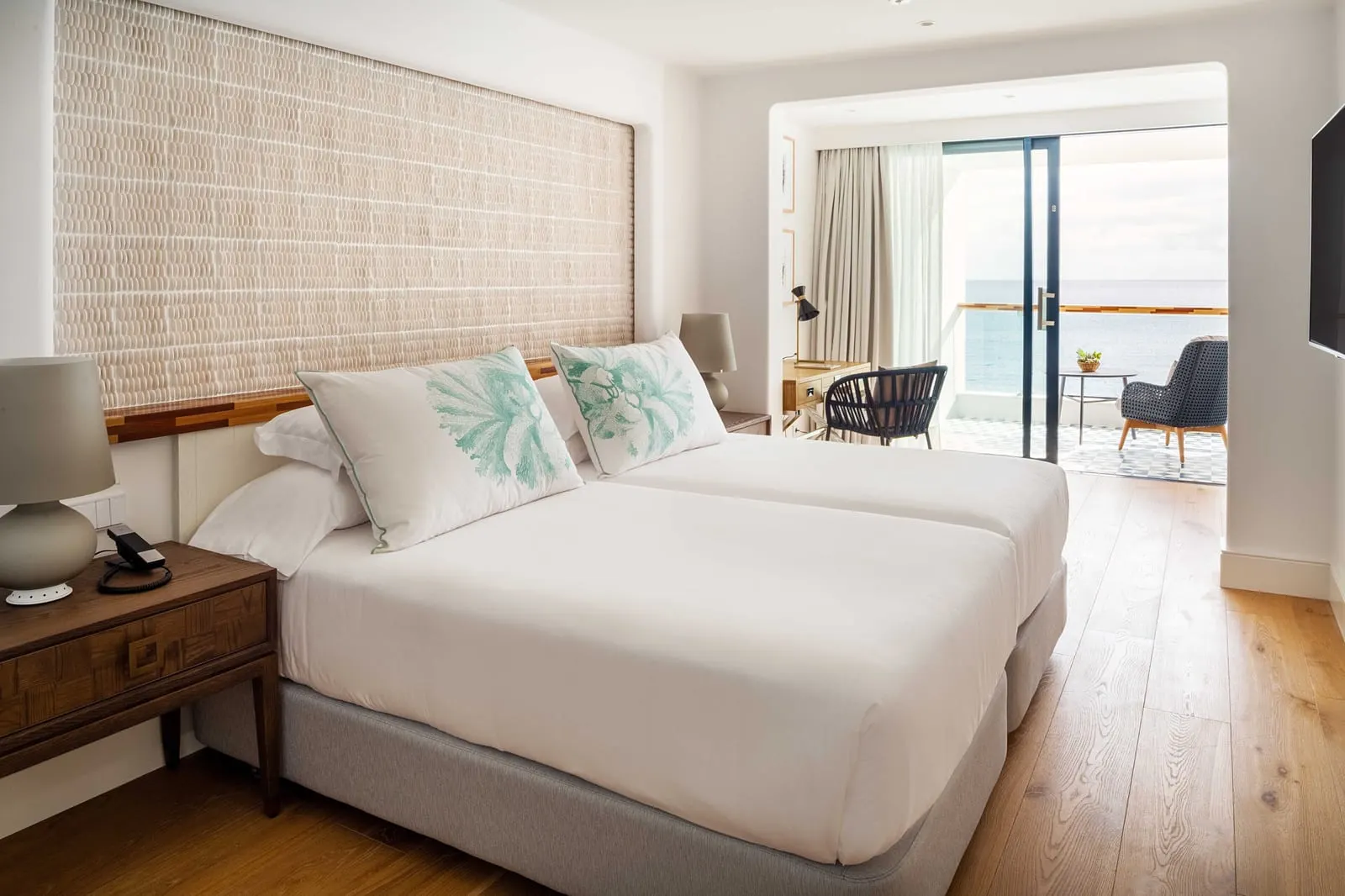 Ocean Suite at Hotel Fariones: two single beds made up as one under a woven headboard wall, with the terrace door beyond