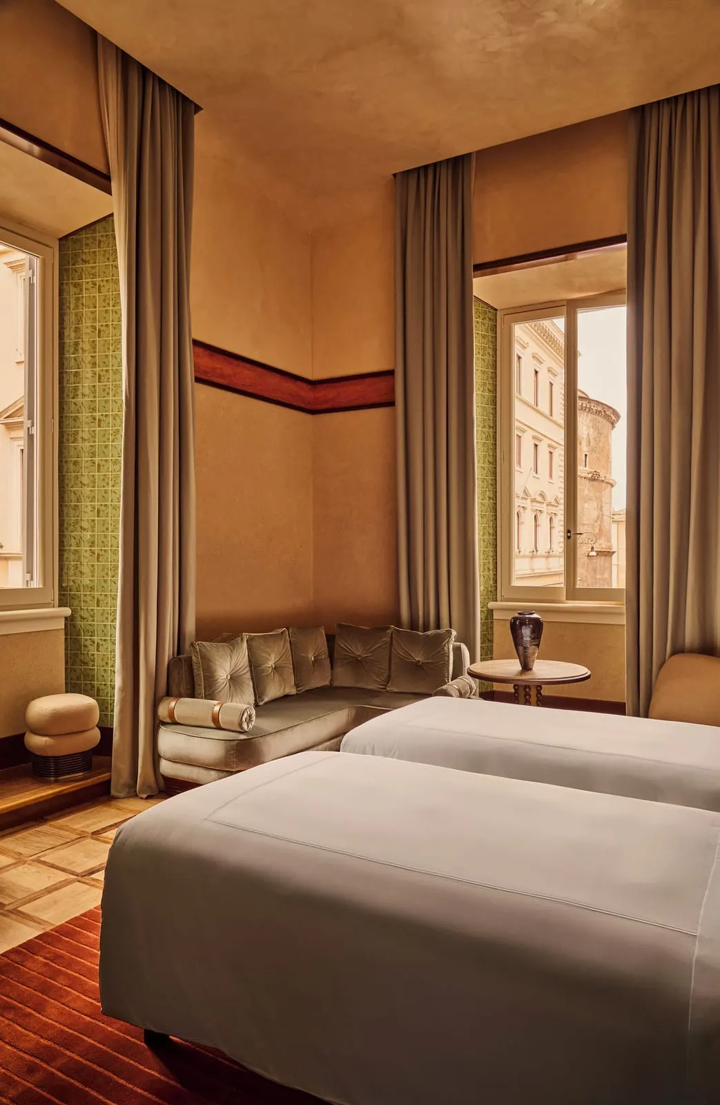 Grand Deluxe Room at Orient Express La Minerva: twin beds, a velvet sofa and two tall windows with green tiled reveals
