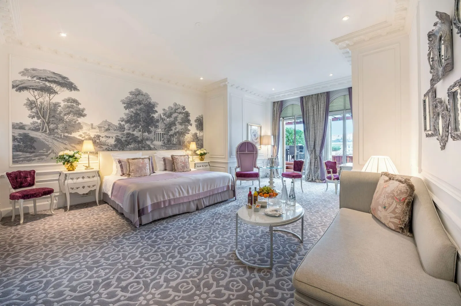 Junior Suite with sea view and jacuzzi at Hôtel Hermitage Monte-Carlo: the bed below a landscape mural, a sofa and a round table