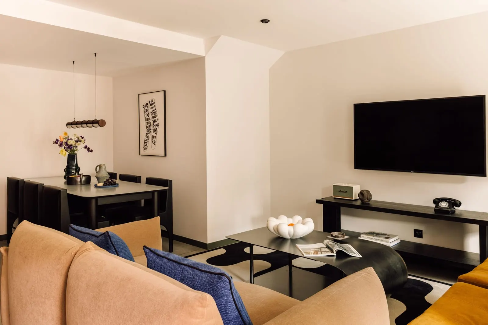 Three Bedroom Duplex Suite at The Rebello: the living room with a sofa and television, and a dining table by the wall