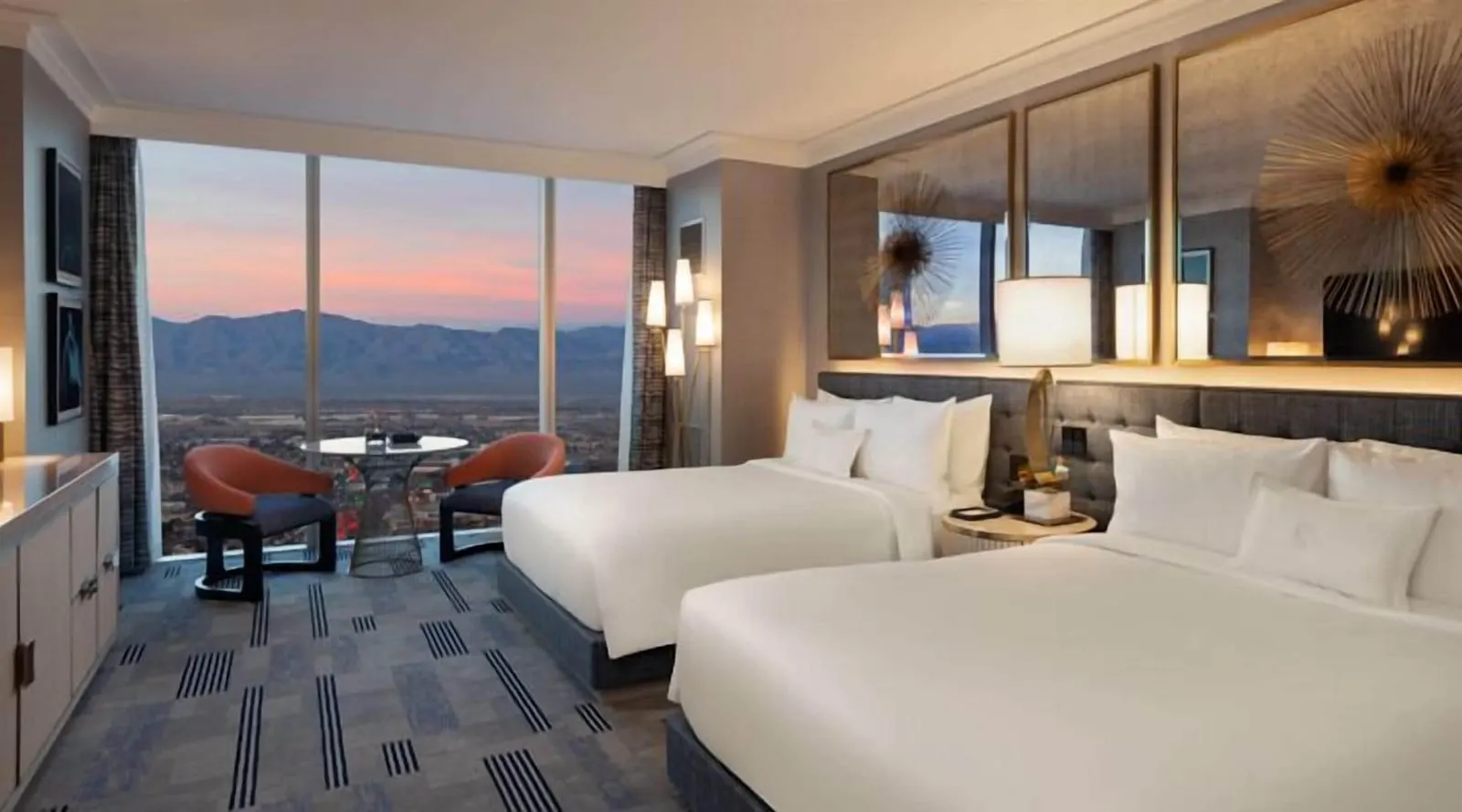 Bleau Queen at Fontainebleau Las Vegas: two queen beds against a tufted headboard under gilt-framed mirrors, with two chairs at a round table by floor-to-ceiling windows