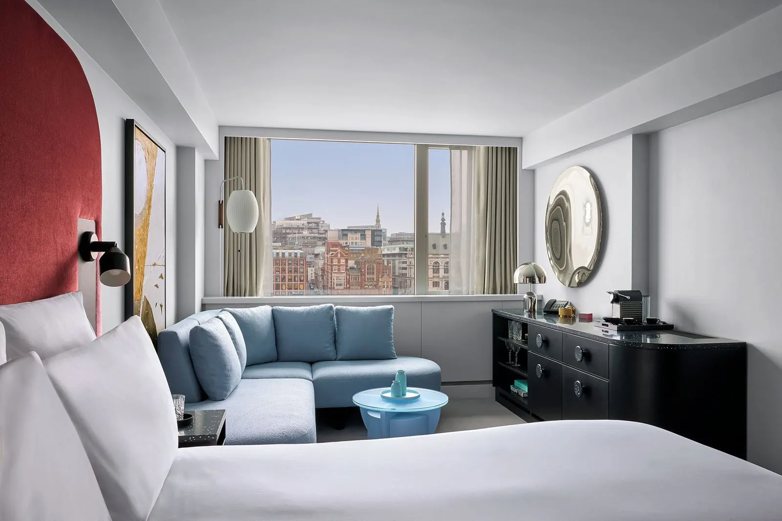 Riverview Studio Suite at Sea Containers London: the bed with a red headboard, a blue sofa and a wide window