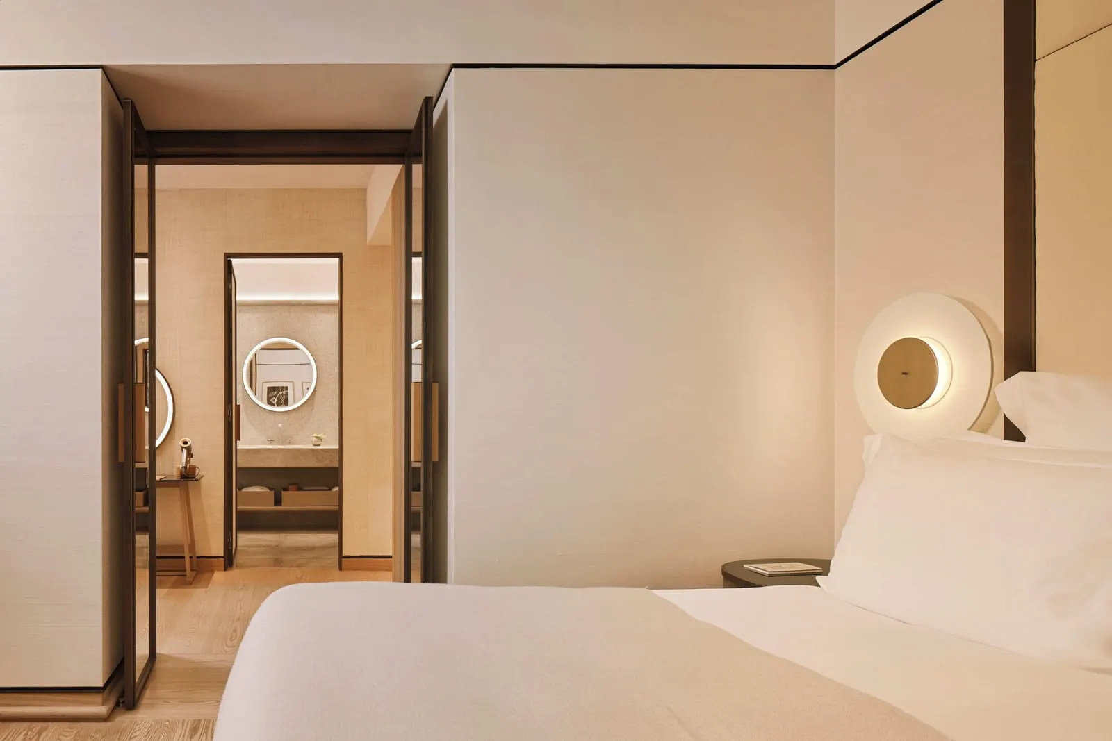 Premium Room at Bvlgari Hotel Roma: the bed and a round wall light, with a dressing room and bathroom beyond