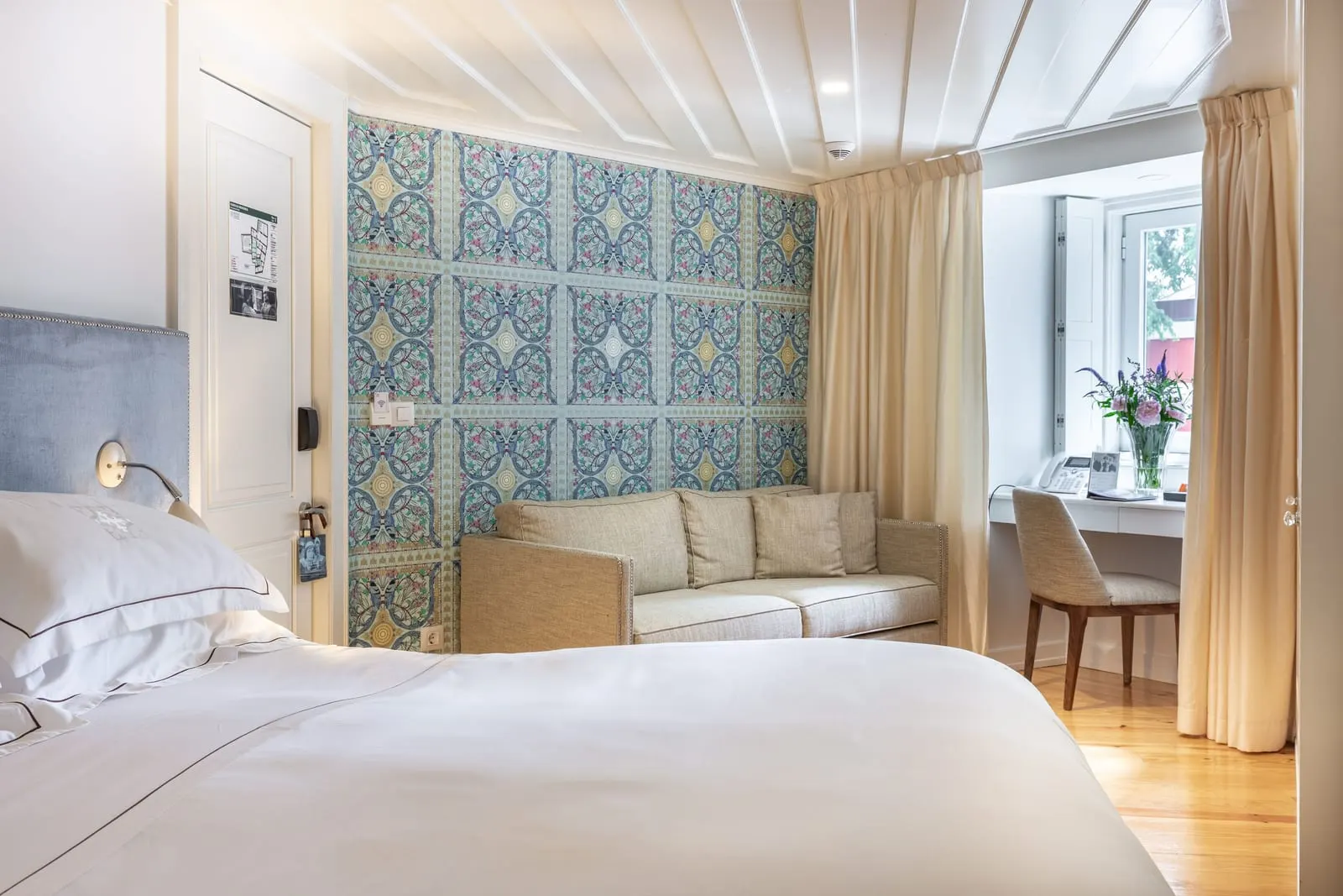Classic Alfama Bedroom at Santiago de Alfama: the bed, a sofa against a blue patterned wall and a desk in the window