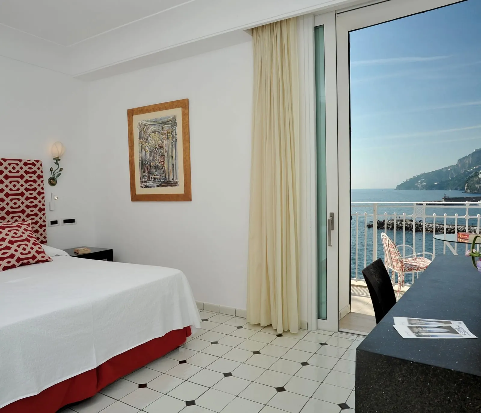 Deluxe（Hotel Marina Riviera）：白いタイルの床のダブルベッドとデスク、湾を見渡す椅子付きのバルコニーへのガラス扉