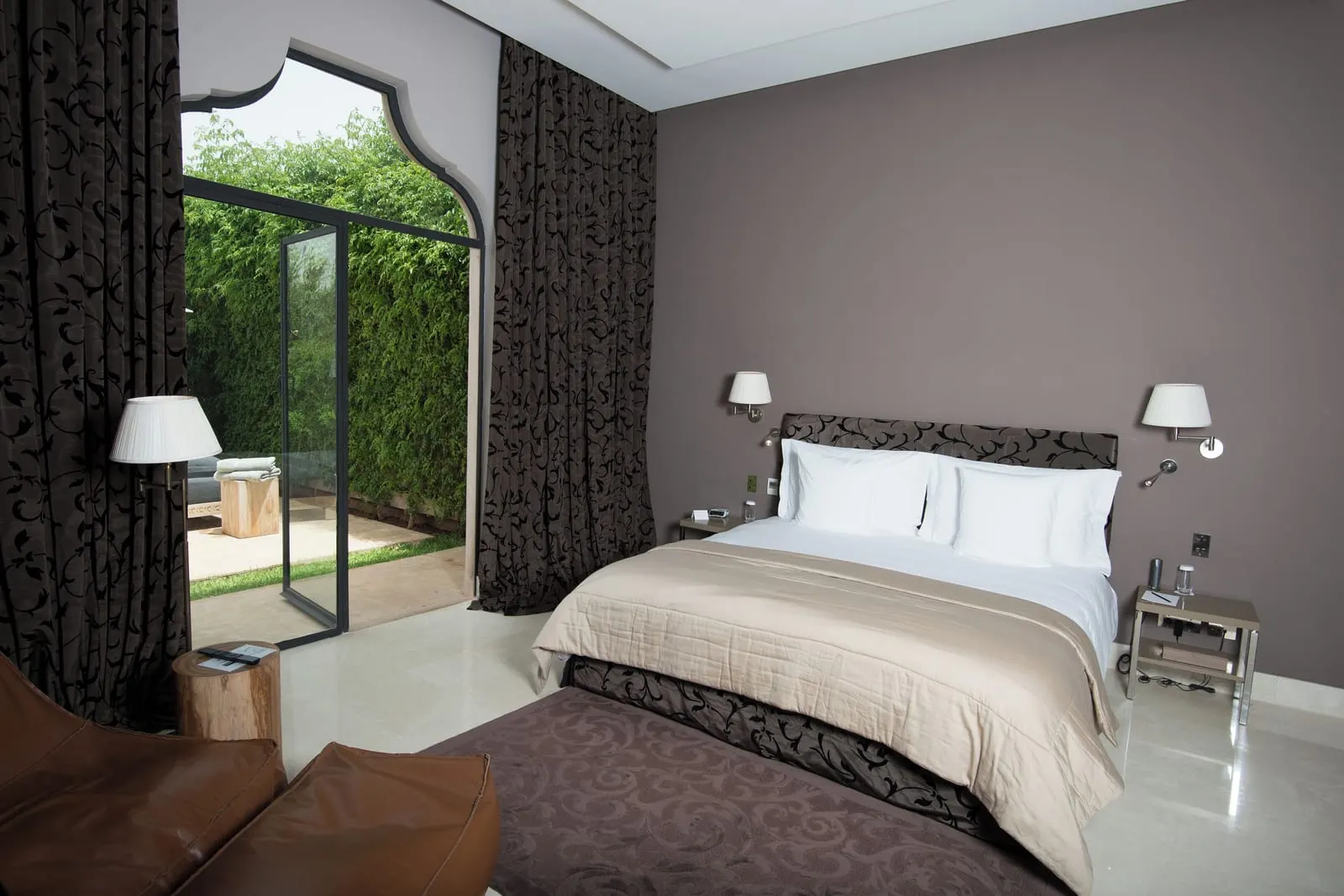 Superior Room at Palais Namaskar: a bed made up as a double beside full-height glass doors onto a small hedged terrace