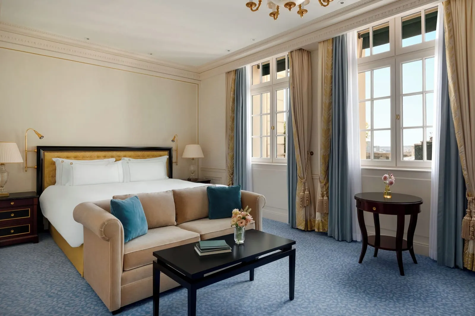 Deluxe Room at Shangri-La Paris: a king bed with a gold headboard, a velvet sofa with teal cushions and two pairs of tall French windows