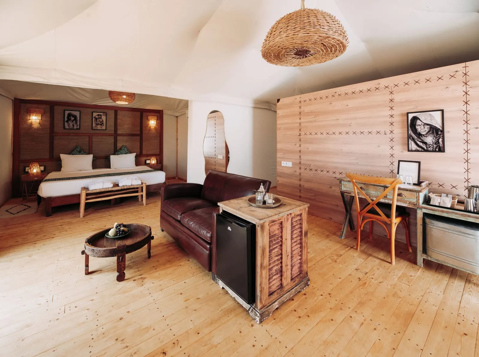 Emotion Suite at Inara Camp: a leather sofa, a low round table and a desk in front of the bed under the white tent roof.