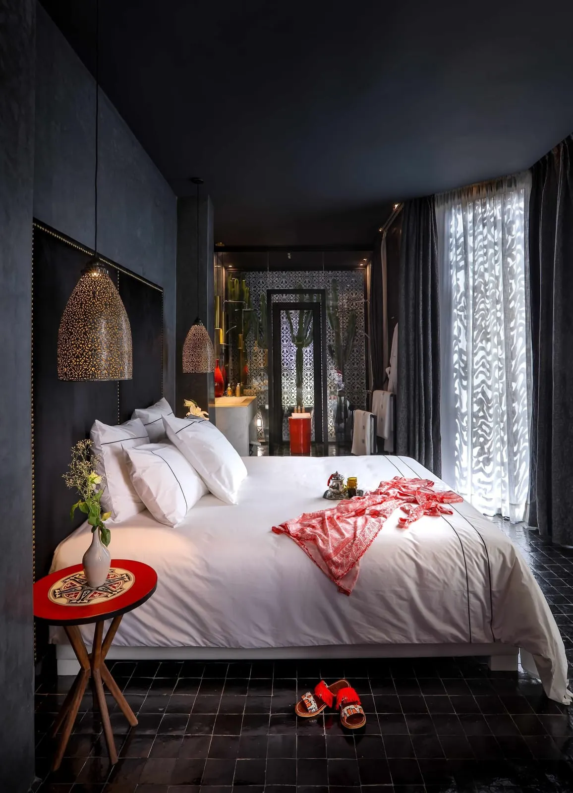 Suite Cactus at Dar Kandi: a white bed in a dark-walled room, with the shower and its cactus garden screen at the far end