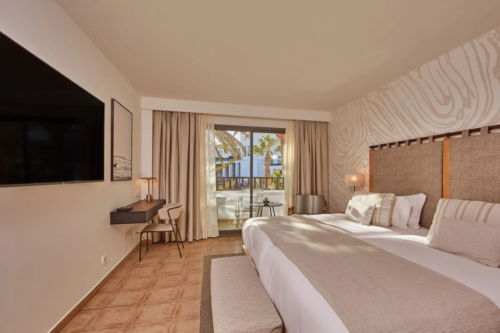 Double Pool View al Secrets Lanzarote Resort & Spa: una camera con un letto, un televisore a parete, una scrivania e porte a vetri sulla terrazza