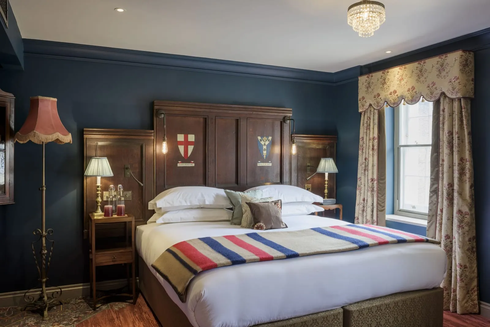 Deluxe King at The Zetter Marylebone: the bed with a panelled headboard, dark blue walls and a tall curtained window