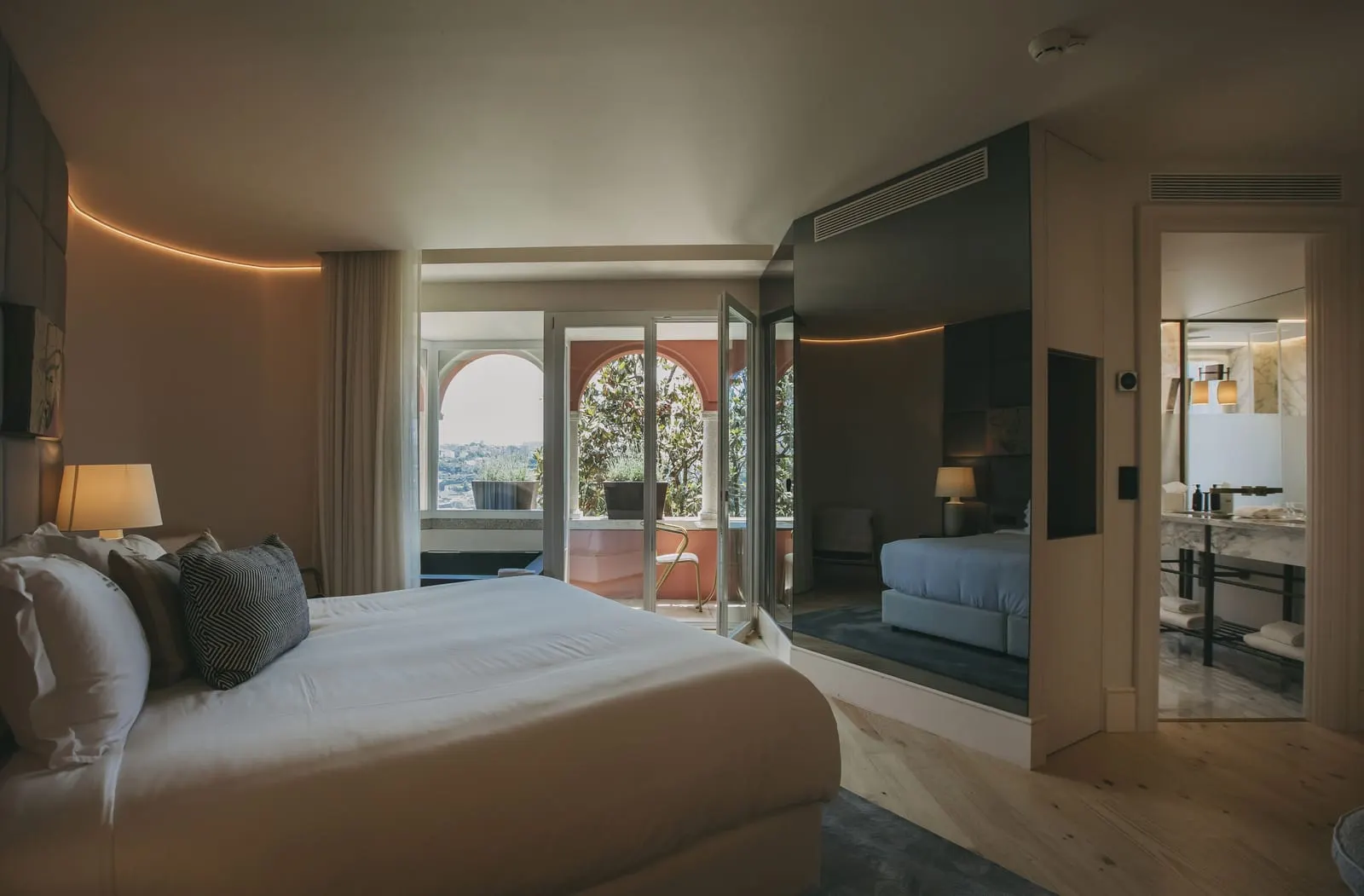 Executive Royal Room at Torel Avantgarde: the bed, a curved wall and glass doors to a terrace framed by red arches