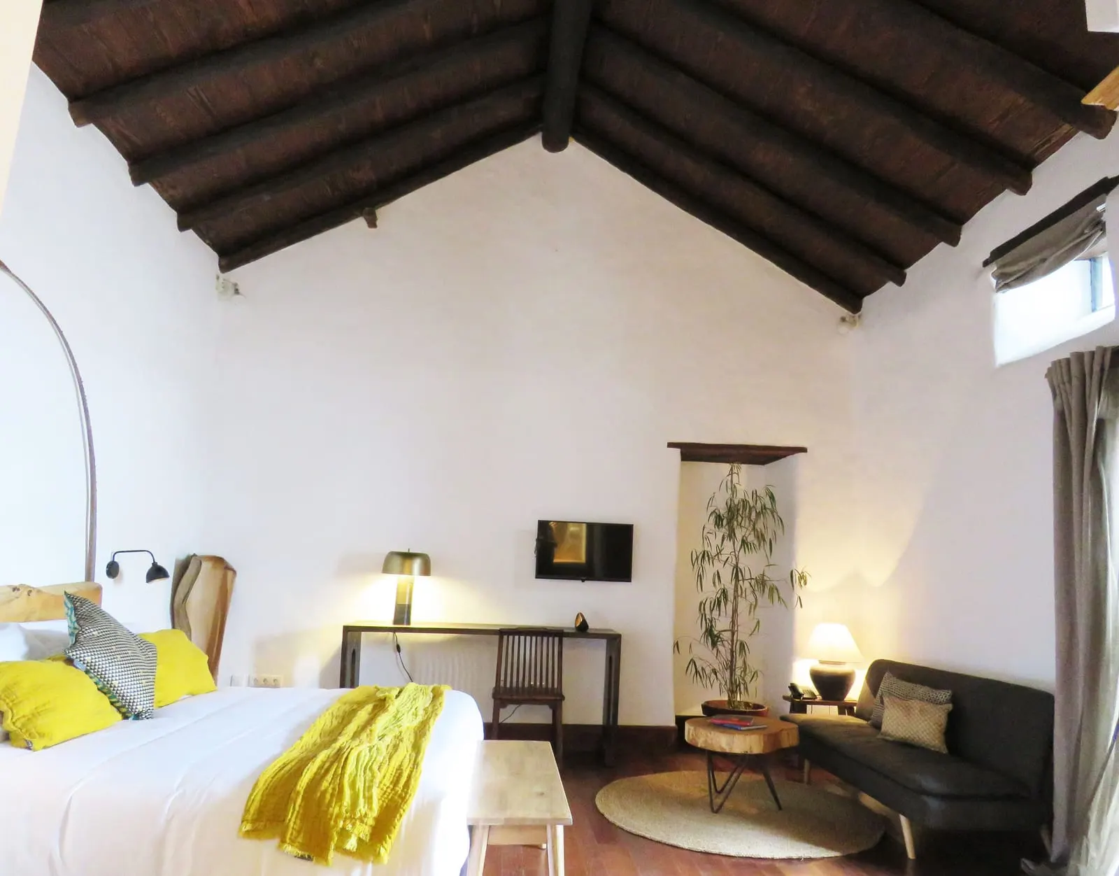 Room 01 at Hotel Boutique Palacio Ico: a high white room under a dark pitched wooden ceiling, with a desk and a lamp