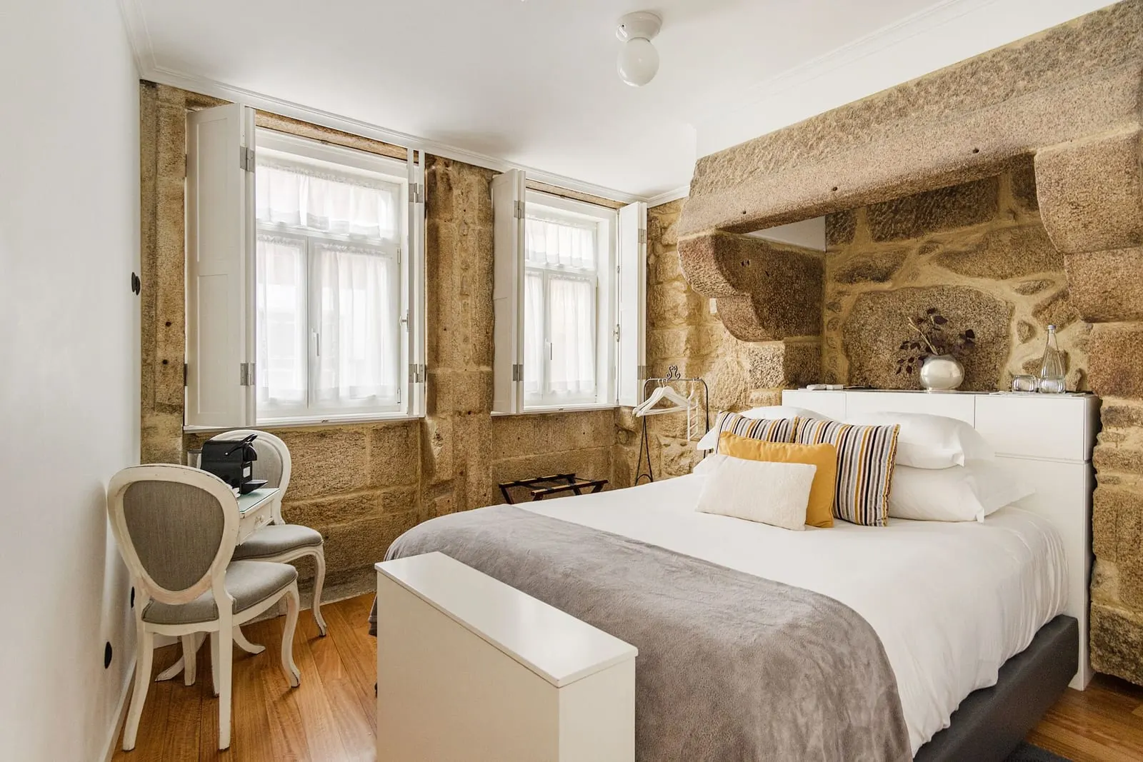 Charm Room with City View at 1872 River House: the bed set into an old granite fireplace, two windows and a small desk